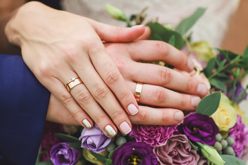 hands of the newlyweds on the wedding bouquet