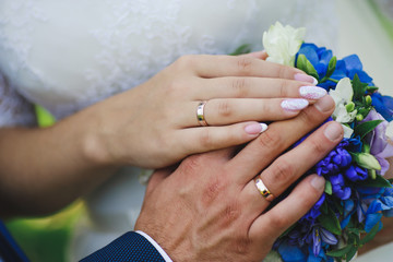 Fototapeta premium hands of the newlyweds on the wedding bouquet