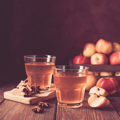 Apple cider, a drink of fresh ripe apples with cinnamon and thyme in a glass beaker on a dark wooden background. Fruit homemade wine. Autumn concept. Soft focus. Toning