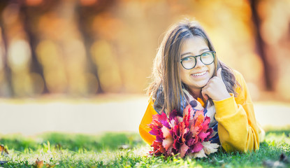 Portrait of a smiling young girl with bouquet of maple leaves.