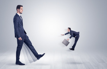 Big man in suit kicking out little himself with simple white wallpaper
