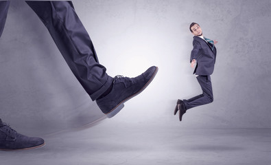 Deported from workplace, big foot kicking small businessman flying away
