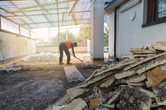 Home Repair. Rebuilding Waterproofing And Insulation Of A Terrace – Roof, Removal And Stacking Of The Old Insulating (polyurethane). Backlit Worker With Pickaxe