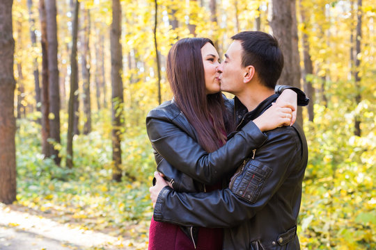 Love, relationship, family and people concept - man kissing his wife in autumn park