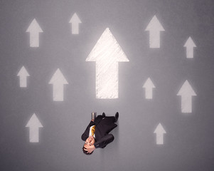 Young contemplating businessman stands in front of white arrows