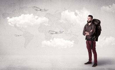 Handsome young man standing with a backpack on his back and planes in front of a world map as a background 