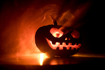 Fototapeta premium Halloween pumpkin smile and scrary eyes for party night. Close up view of scary Halloween pumpkin with eyes glowing inside at black background.