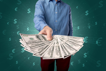 Young businessman holding large amount of bills with green background and currency symbols 