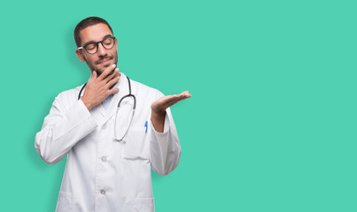 Doubtful young doctor showing something with his hand