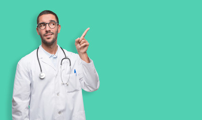 Doubtful young doctor pointing up