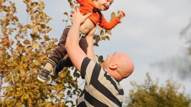 Concept happy family. Father throwing his adorable son in the air.