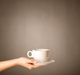 Young female hand holding coffee cup with brown background