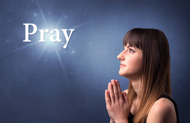 Young woman praying on a blue background with the word Pray written above her