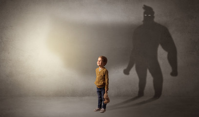 Cute kid in a room with plush on his hand and hero shadow on his background
