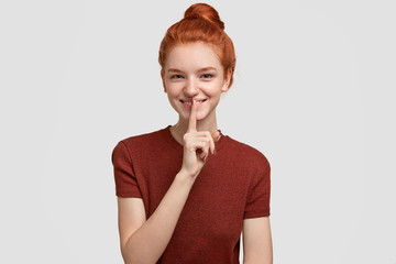 Keep this in secret. Mysterious happy red haired freckled girl makes shush gesture, has positive expression, asks not spread her private information, gossips with best friend. Conspiracy concept
