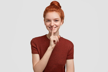 Keep this in secret. Mysterious happy red haired freckled girl makes shush gesture, has positive...