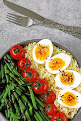 Buddha bowl with bulgur, green beans, cherry tomatoes and boiled egg halves. Healthy food in a bowl. The concept of dietary nutrition.