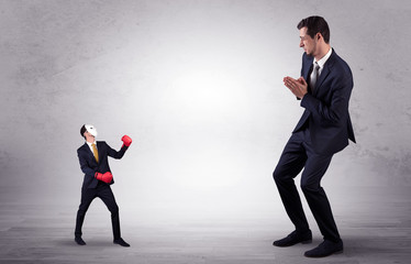 Big businessman being afraid of small masked businessman with box gloves in an empty room concept
