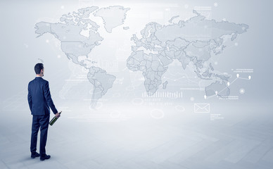 Businessman standing with his back and looking at a worldwide map with objects in his hand
