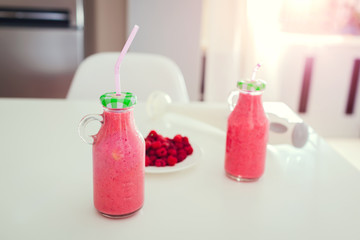 Two bottles of fruity smoothie ready to drink on kitchen table. Healthy eating