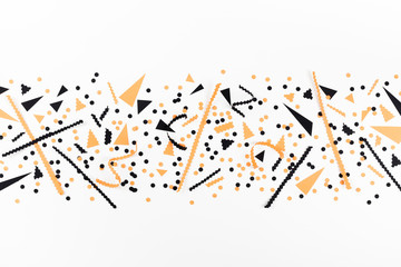 Minimalistic Halloween party decorations from black and orange confetti top view. Flat lay.