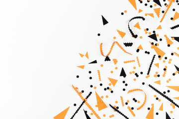 Halloween party decorations from black and orange confetti top view. Flat lay style.