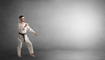 Small karate man fighting in an empty grey copy space