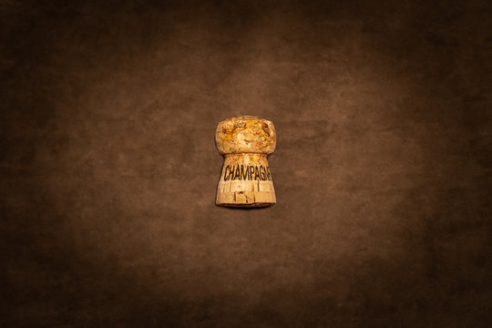 One champagne cork with text against brown suede texture seen from above.