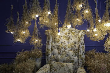 sofa, dry yellow flowers and light bulb hanging.