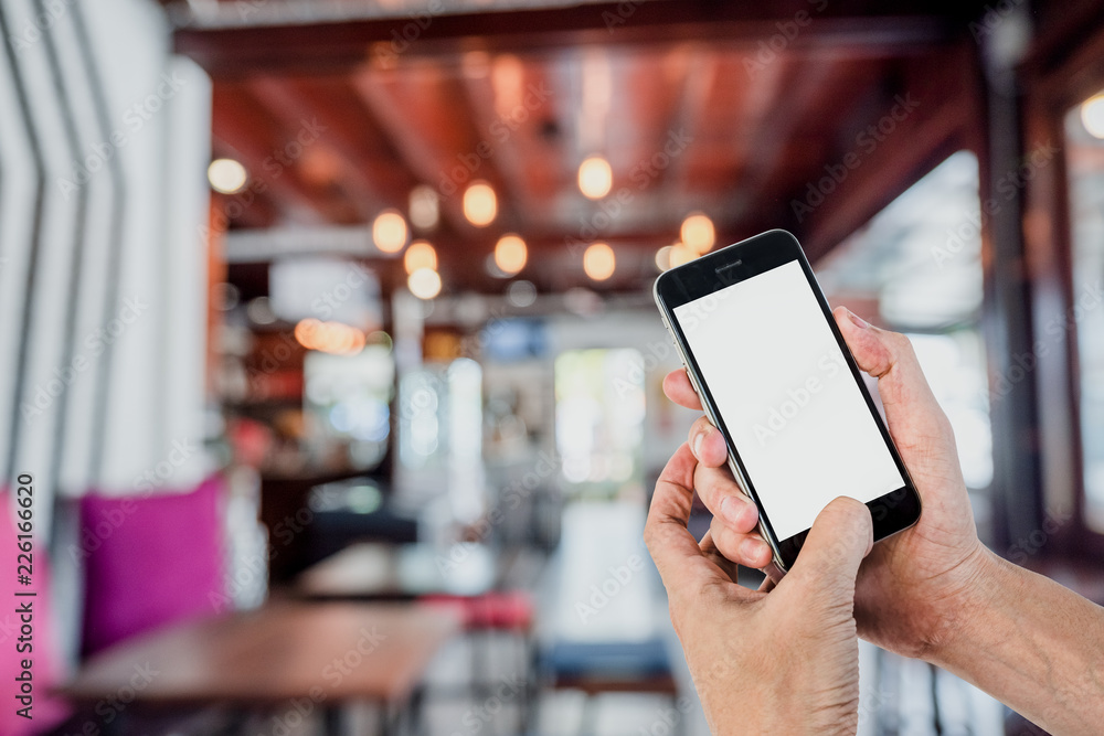 Poster man hands using smart phone with blurred coffee cafe background. blank screen for graphics display m