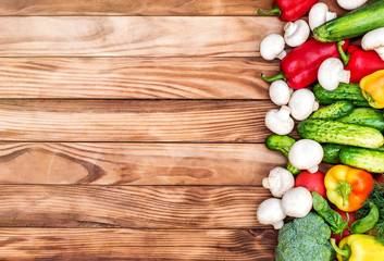 Border from different vegetables on wooden background. Top view. Space for text.