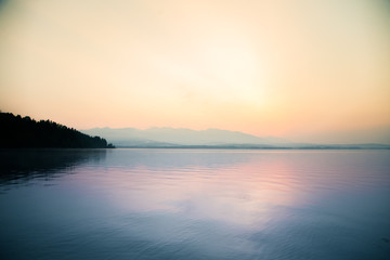 A beautiful, calm morning landscape of lake and mountains in the distance. Colorful summer scenery with mountain lake in dawn. Tatra mountains in Slovakia, Europe.