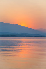 A beautiful, calm morning landscape of lake and mountains in the distance. Colorful summer scenery with mountain lake in dawn. Tatra mountains in Slovakia, Europe.