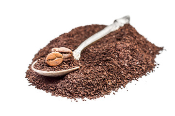 Spoon on heap of ground coffee and coffee beans on white.