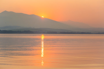 A beautiful, calm morning landscape of lake and mountains in the distance. Colorful summer scenery with mountain lake in dawn. Tatra mountains in Slovakia, Europe.