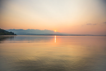 Obraz premium A beautiful, calm morning landscape of lake and mountains in the distance. Colorful summer scenery with mountain lake in dawn. Tatra mountains in Slovakia, Europe.