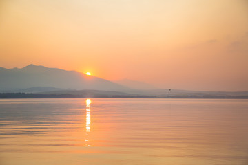 A beautiful, calm morning landscape of lake and mountains in the distance. Colorful summer scenery with mountain lake in dawn. Tatra mountains in Slovakia, Europe.