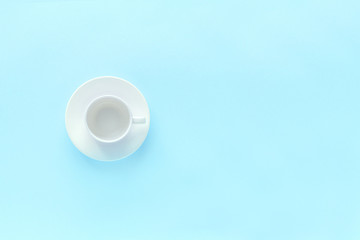 empty white coffee cup and dish saucer on blue background