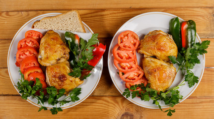 Fried chicken with vegetables on a round plate on a wooden table.