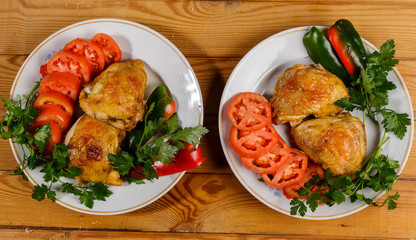 Fried chicken with vegetables on a round plate on a wooden table.