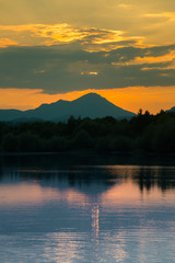 Obraz premium A beautiful, colorful sunset landscape with lake, mountain and forest. Natural evening scenery over the mountain lake in summer. Tatra mountains in Slovakia, Europe.