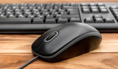 Computer keyboard with computer mouse on wooden table. Close up.