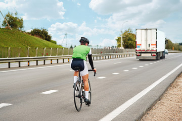 Road cyclist wearing helmet, riding a race at high speed, during a time trial contest on the...