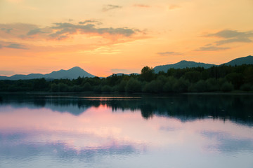 A beautiful, colorful sunset landscape with lake, mountain and forest. Natural evening scenery over the mountain lake in summer. Tatra mountains in Slovakia, Europe.