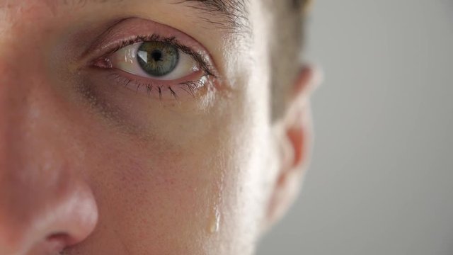Half face portrait of depressed man crying with tears in eye. Man in despair.