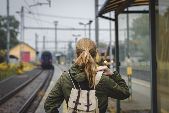 Woman with backpack is looking at the departing train. Travelling during autumn season. Travel concept