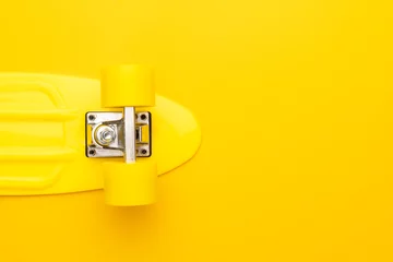 Rollo plastic mini cruiser board on yellow background. bright yellow cruiser skateboard with copy space © Ruslan Grumble