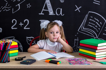 Schoolgirl sitting at the desk with books, school supplies ready to write in the exercise book