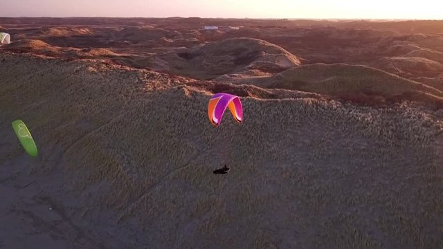 Drone/Aerial shot of a parapenter flying over the duns ot the Netherlands. Shot was made by a professional drone pilot.