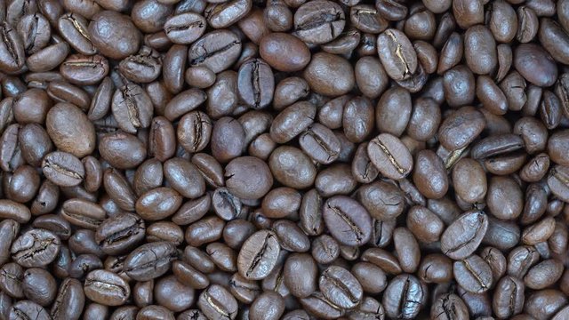 Fried coffee beans background, close up, rotation loopable 4k top view. Food  background. Gastronomy concept, organic food. Macro coffee beans